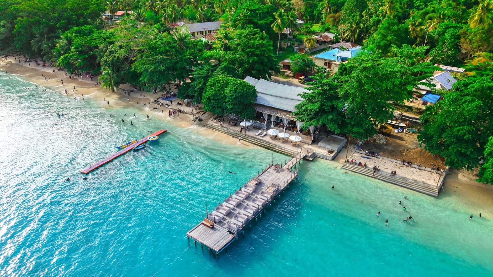 Stunning aerial shot of Manokwari beach, featuring clear turquoise waters and lush greenery.